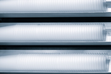 Aufkleber - Three rows of white plastic cups are stacked on top of each other. The cups are all the same size and shape, and they are all white. The image has a clean and organized look