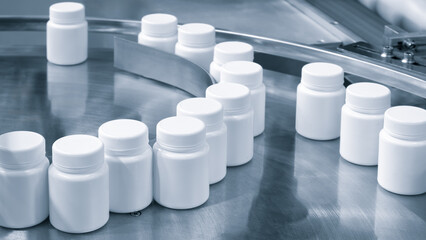 Poster - Row of white plastic containers with lids for medicines or vitamins or active dietary supplements on conveyor belt of pharmaceutical factory