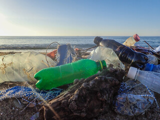 Spilled garbage on the beach of the big city. Empty used dirty plastic bottles. Dirty sea sandy shore the Mediterranean Sea. Environmental pollution. Ecological problem. Moving waves in the background