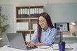 © Crystal - Young Asian businesswoman working on laptop in modern office