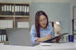 © Crystal - Asian businesswoman writing notes on clipboard while working at office desk