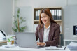 © Crystal - Young Asian businesswoman smiling and working using laptop in modern office