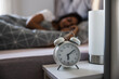 © milanmarkovic78 - Alarm Clock On Bedside Table Near Sleeping Woman