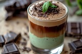 A decadent chocolate mint latte with a creamy layer of mint syrup and chocolate flakes on top.