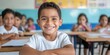© Y_Malashkevych - A cheerful Hispanic boy around six years old is smiling directly at the camera in a bright classroom