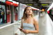 © JackF - Young woman in headphones with phone standing at metro station