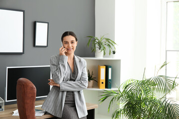 Sticker - Female office worker talking on mobile phone near armchair and workplace in stylish office