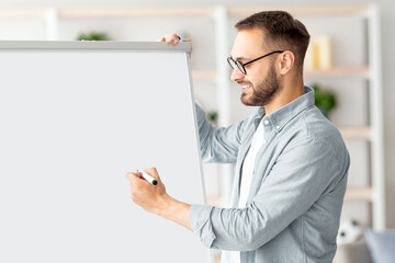 Poster - Young Caucasian male teacher giving online class, explaining English rules, writing on blackboard at home office. Remote tutoring and distance education during coronavirus lockdown concept
