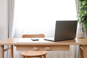 Laptop with blank white screen on wooden desk, home office, work from home.