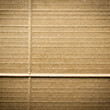 © homydesign - Corrugated cardboard surface with horizontal lines and a vertical crease creating a simple geometric pattern