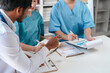 © Ratirath - Two male doctors and a female nurse meet at a table in the hospital, collaborating on medical tasks, using laptops and computers, showcasing teamwork,and focusing on health,medicine,and patient care