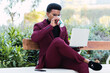 © BUDDHA - Handsome businessman using laptop and drinking take away coffee in the park