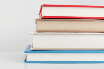 Poster - Stack of hardcover books with colorful bindings on a light background.