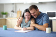 © Antonioguillem - Happy interracial couple signing paper contract at home