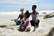 © Westend61 - Mother with daughter and friend doing a yoga exercise on the beach