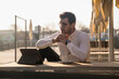 © Westend61 - Young man with tablet at outdoor cafe