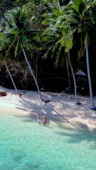 Wall Mural - Enjoying a tranquil day on Koh Wai Island, Thailand, where crystal-clear waters meet soft sandy shores. Two adventurers embrace nature beneath towering palm trees, reveling in paradise.