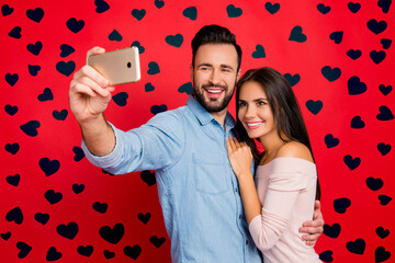 Poster - Portrait of young, caucasian, attractive, lovely, cute, smiling, positive, couple, man making selfie with his wonderful woman on smart phone over red background, 14 february