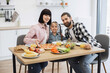 © sofiko14 - Caucasian family with father, mother, and daughter enjoying pizza and fruit for breakfast at home. Happy morning meal in bright kitchen setting with fresh produce and orange juice.