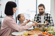 © sofiko14 - Caucasian family including parents and young daughter enjoying breakfast together with pizza and salad at home. Bright, casual atmosphere conveys warmth and togetherness among family members.