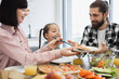 © sofiko14 - Caucasian family having breakfast with pizza and salad. Young parents with daughter sharing meal. Bright kitchen setting, creating joyful and warm family atmosphere.