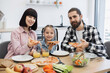 © sofiko14 - Caucasian family with parents and daughter having breakfast with pizza. Family smiles while dining together in bright kitchen, showing happiness and togetherness.