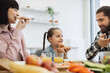 © sofiko14 - Caucasian family with young child enjoying breakfast together at home. Mother, father, and daughter sharing pizza and orange juice, creating a warm, joyful atmosphere.