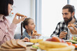 © sofiko14 - Caucasian family having pizza for breakfast at home. Parents and daughter enjoying meal together, sharing smiles and conversations.
