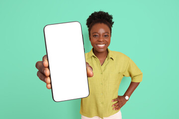 Happy woman showing mobile phone with blank screen on aquamarine color background. Mockup for design