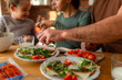 © DusanJelicic - Close-up of a parent's hands chopping vegetables on the kitchen counter as their child observes the meal preparation.