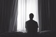 © Sean Hoong - A lone man staring out of a window, with the curtains drawn around him, creating a peaceful and reflective moment of solitude in his bedroom.