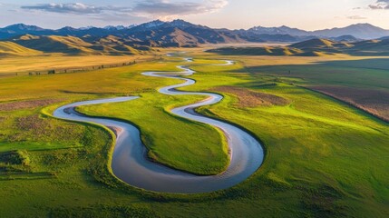 Wall Mural - Aerial view meandering river, green valley, mountain backdrop, sunset