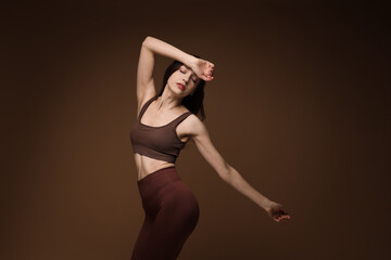 Wall Mural - Beautiful woman in stylish sportswear on brown background