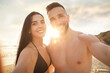 © New Africa - Happy young couple taking selfie on beach at sunset
