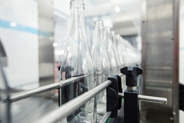 Poster - process of filling glass bottles on an assembly line in a modern production facility during daytime 