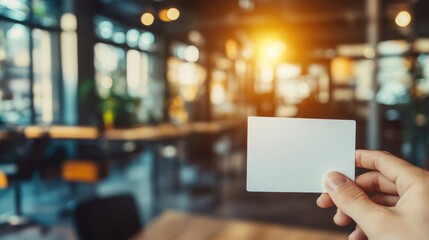 Aufkleber - Hand holding a blank business card in a blurred modern office setting with ample copy space for text or branding purposes.