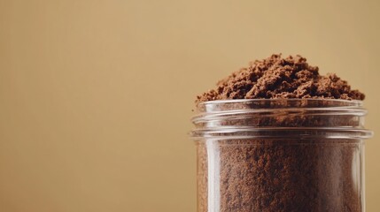 Poster - Close up of a glass jar filled with freshly ground coffee against a soft beige background for text placement and branding opportunities