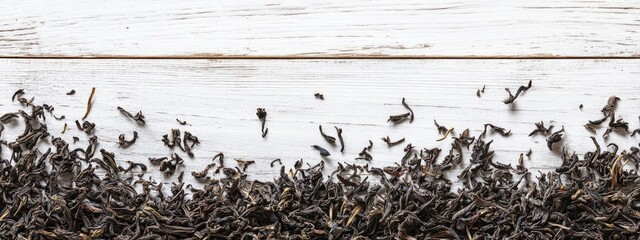 Fototapete - Dried tea leaves scattered on a white wooden surface with ample empty space for text or design elements above