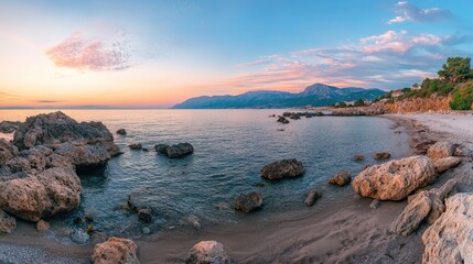 Poster - Serene sunset over a tranquil rock beach with diverse stones highlighting the sandy shore and calm sea under a colorful sky