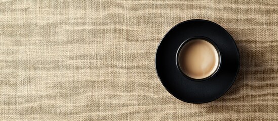 Poster - Black coffee saucer on beige textile background with empty space for text ideal for promotional or editorial use in food photography
