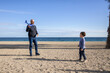 © Miri García - Father and son playing with toy airplane on beach