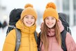© tengah - Two young women smiling in winter jackets and hats while enjoying a snowy outdoor adventure