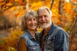 © Markus Schröder - Portrait of a cheerful couple in their 50s wearing a rugged jean vest in front of background of autumn leaves