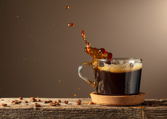 Wall Mural - Black coffee in glass cup on a brown background.