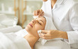 © Studio Romantic - Relaxed young woman enjoying facial treatment at spa salon. Professional beautician or cosmetologist in white coat wipes off makeup or refreshing AHA peel from woman's face. Skin care, beauty concept