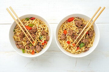 Canvas Print - Two bowls of Chow Mein or Lo Mein Chinese stir fried noodles with meat and veggies served with chopsticks on a rustic wooden table