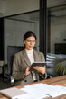 © Stock 4 You - Vertical portrait of young latin professional business woman working on tab pc computer. Middle eastern businesswoman holding digital tablet using pad application sitting at desk workplace in office.