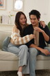 © supAVADEE BUTRADEE - Asian couple, wife hugging husband, sitting on sofa together happy in living room at home, creating a warm and loving family in a new home.