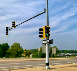 Green traffic light allowing traffic to proceed on a one-way street on a sunny day