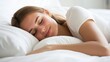 © InfiniteStudio - Woman sleeping peacefully in a soft bed surrounded by fluffy pillows during morning light